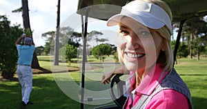 Happy female golfer sitting in golf buggy