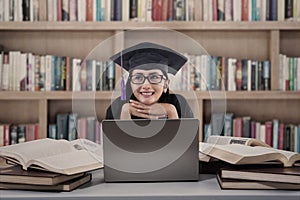 Happy female graduate thinking at library