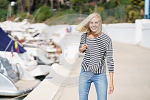 Happy female in her 60s strolling along a seaside spot near the beach.