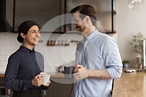 Happy female indian employee communicating with male colleague.