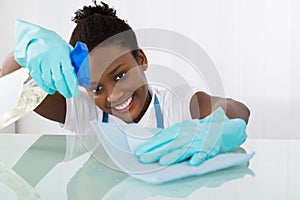 Happy Female Janitor Cleaning Desk With Rag