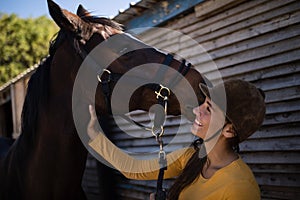 Happy female jockey stroking horse