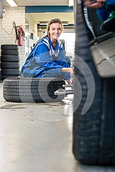 Happy Female Mechanic Changing Car Tire At Automobile Shop