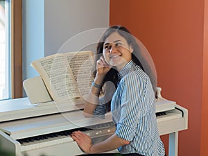 Happy female musician playing piano indoor