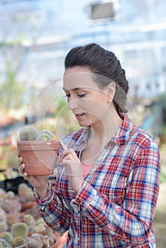 Happy female nursery owner with pot flowers inside greenhouse