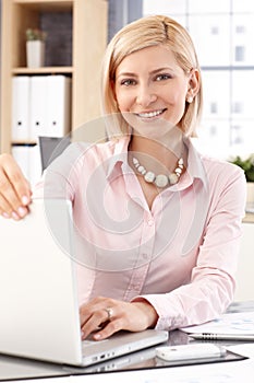 Happy female office worker with laptop computer