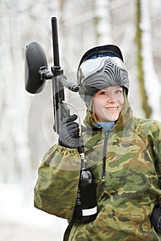 Happy female paintball player with marker at winter outdoors
