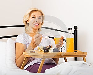 Happy female pensioner having breakfast