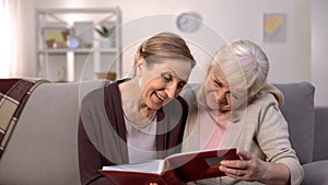 Happy female pensioners admiring old photos in album, retirement leisure, fun