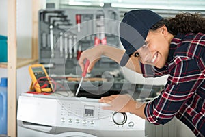 happy female plumber working on washing machine