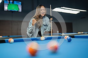 happy female pool player clenched her arms after poking the billiard ball