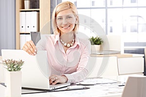 Happy female receptionist with laptop computer