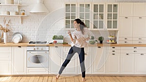 Happy female renter enjoy dancing in home kitchen