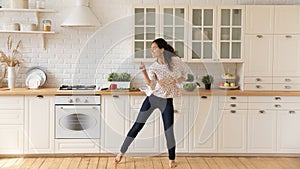 Happy female renter enjoy dancing in home kitchen photo