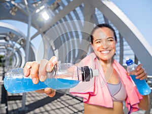 Happy female runner with energetic drinks for hydration