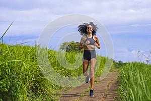 Happy female runner training on countryside road - young attractive and fit jogger woman doing running workout outdoors at