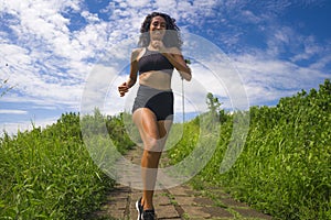 Happy female runner training on countryside road - young attractive and fit jogger woman doing running workout outdoors at