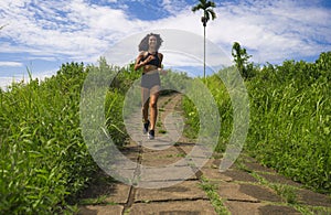 Happy female runner training on countryside road - young attractive and fit jogger woman doing running workout outdoors at