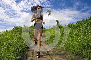 Happy female runner training on countryside road - young attractive and fit jogger woman doing running workout outdoors at