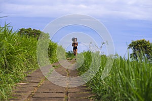 Happy female runner training on countryside road - young attractive and fit jogger woman doing running workout outdoors at