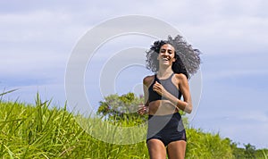 Happy female runner training on countryside road - young attractive and fit jogger woman doing running workout outdoors at