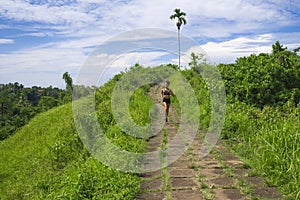 Happy female runner training on countryside road - young attractive and fit jogger woman doing running workout outdoors at