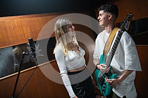 Happy female singer and male guitarist in sound recording studio