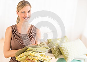 Happy Female Store Owner Holding Sheets In Bedding Store