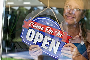 Happy Female Store Owner Turning Open Sign in Window