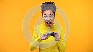 Happy female student with game joystick yellow background, hobby excitement