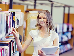 Happy female student holding books at the library