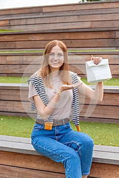 Happy female student holding a paper bag