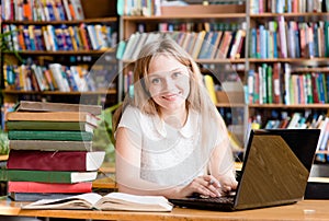 Happy female student with laptop in library