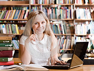 Happy female student with laptop in library