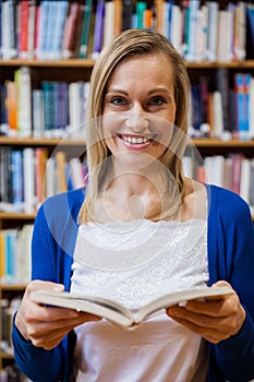 Happy female student reading a book in the library