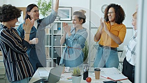 Happy female team doing high-five joining hands and applauding standing in workplace together