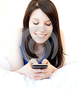 Happy female teenager using cellphone on the bed