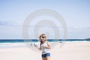 Happy female tourist enjoy leisure outdoors at the beach listening music from mobile phone and headset amiling and enjoying summer