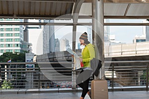 Happy female tourist with suitcase exploring map while standing