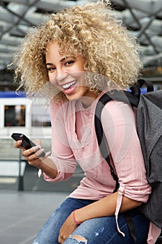 Happy female traveler with backpack and phone