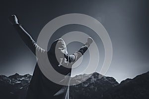 Happy female traveler with hands raised at mountain top