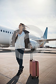 Happy female traveler with her luggage outdoors