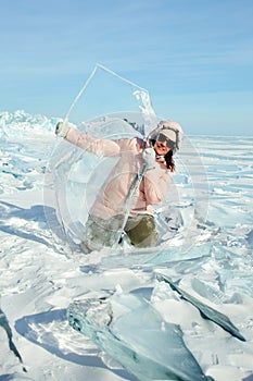 A happy female traveler holds an ice floe transparent as glass in her hands.