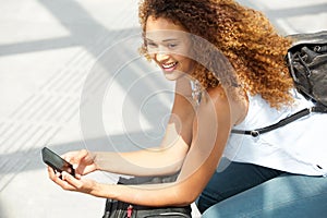 Happy female traveler sitting with bags and mobile phone