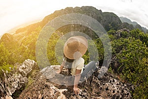 Happy female traveler sitting on top of a mountain.