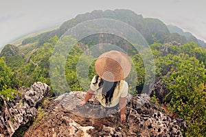 Happy female traveler sitting on top of a mountain.