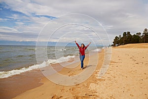 A happy female traveler walks on a sandy beach. Summer vacation