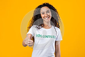 Happy Female Volunteer Gesturing Thumbs Up Standing Over Yellow Background