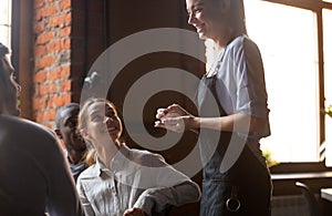 Happy waitress holding notepad taking order serving clients in cafe