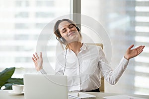 Happy female worker enjoying favorite music at work photo